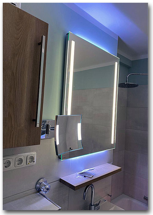 Beleuchtungsspiegel im Bad mit vertikaler Spiegelbeleuchtung rechts und links und zusätzlicher Raumbeleuchtung nach oben und unten. Die Beleuchtung des Spiegel erfolgt mit LED und ist dimmbar.